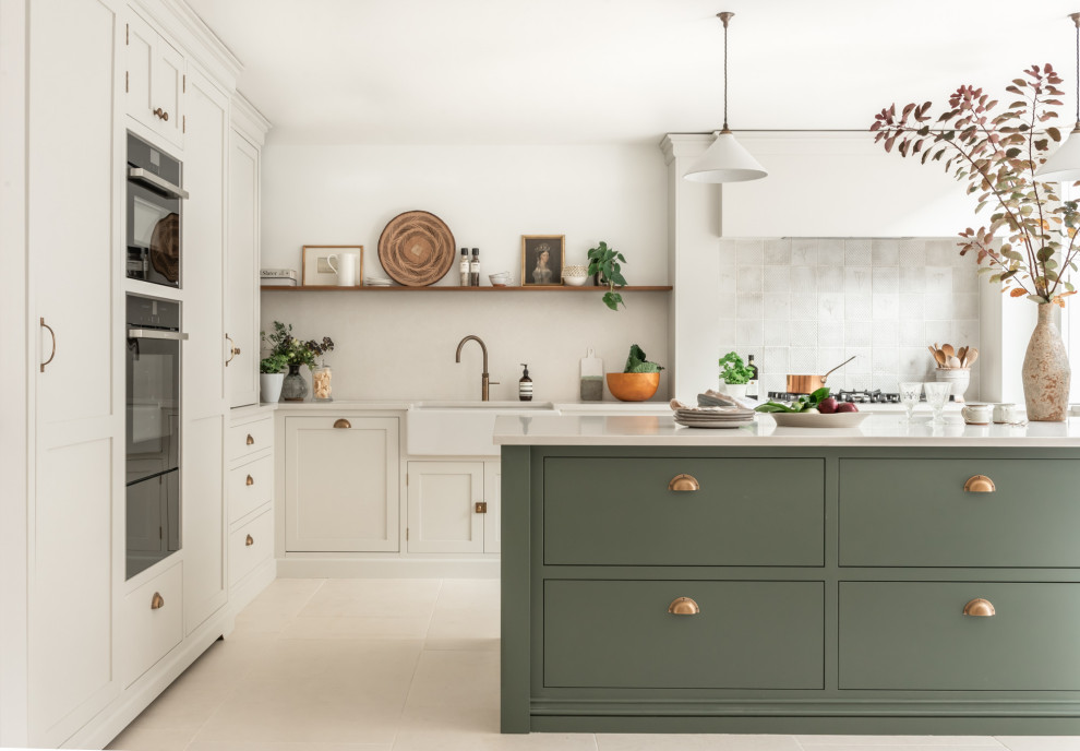 This is an example of a large transitional l-shaped eat-in kitchen in Surrey with a farmhouse sink, shaker cabinets, green cabinets, quartzite benchtops, white splashback, stone tile splashback, black appliances, ceramic floors, with island, beige floor and white benchtop.