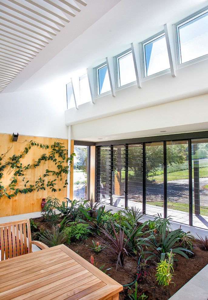 Large contemporary open concept living room in Wollongong with limestone floors, a wood stove, a tile fireplace surround, a concealed tv, white walls and grey floor.