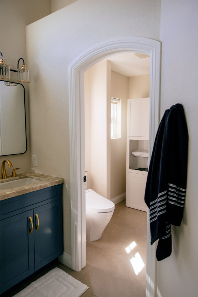This is an example of a large modern master bathroom in San Diego with shaker cabinets, blue cabinets, a freestanding tub, a double shower, a one-piece toilet, white tile, porcelain tile, white walls, porcelain floors, an undermount sink, quartzite benchtops, grey floor, a hinged shower door, beige benchtops, an enclosed toilet, a double vanity, a built-in vanity and vaulted.