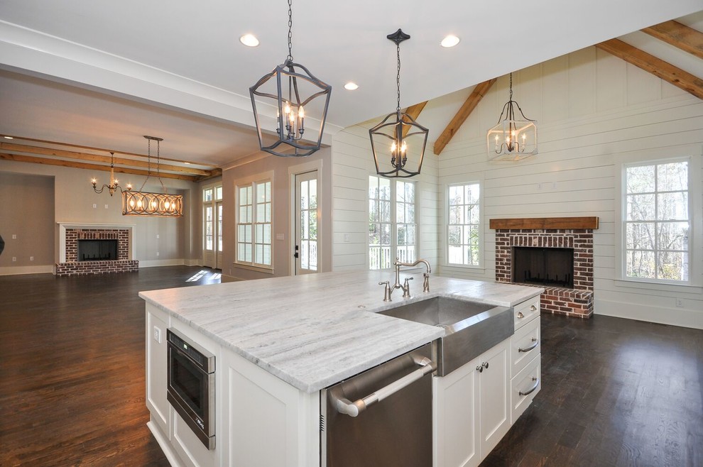 Photo of a mid-sized contemporary l-shaped open plan kitchen in Atlanta with a farmhouse sink, shaker cabinets, white cabinets, granite benchtops, white splashback, subway tile splashback, stainless steel appliances, dark hardwood floors, with island and brown floor.