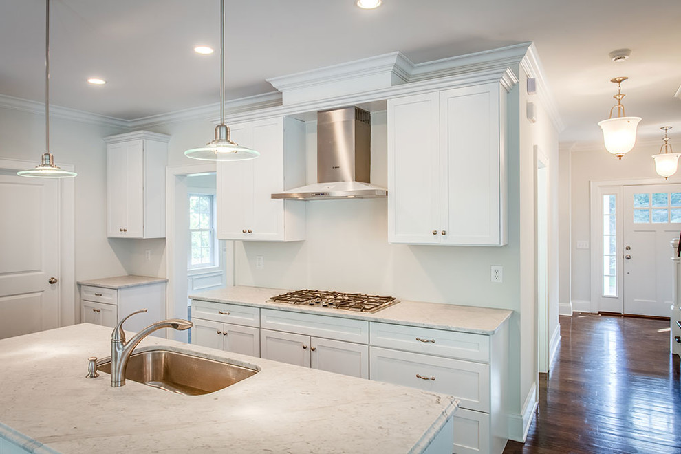 Example of a large transitional l-shaped dark wood floor and brown floor eat-in kitchen design with an undermount sink, shaker cabinets, white cabinets, white backsplash, stainless steel appliances and an island