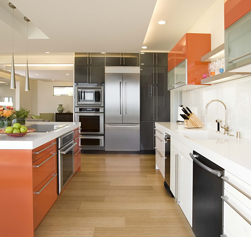 Photo of a contemporary galley kitchen in San Francisco with flat-panel cabinets, orange cabinets, white splashback, glass sheet splashback, stainless steel appliances and bamboo floors.