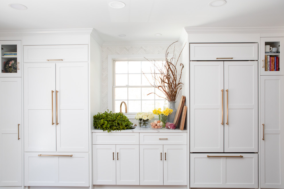 Inspiration for a large transitional l-shaped medium tone wood floor open concept kitchen remodel with an undermount sink, shaker cabinets, white cabinets, quartz countertops, gray backsplash, marble backsplash, paneled appliances, an island and white countertops