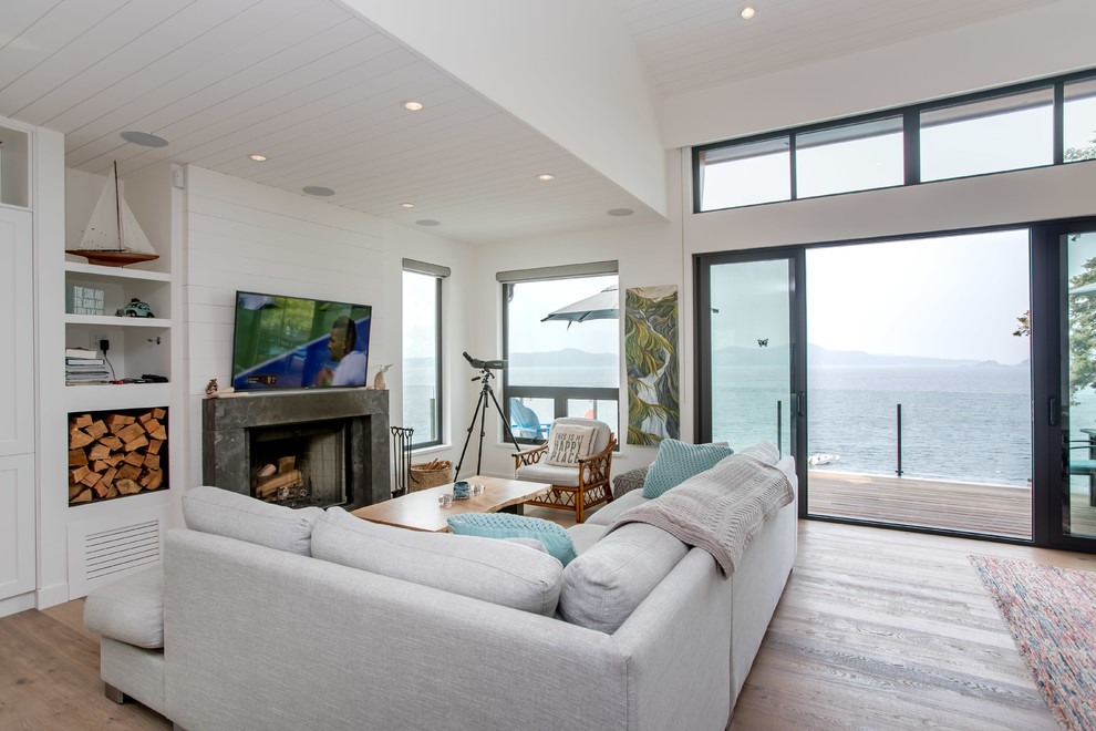 Beach style open concept living room in Vancouver with white walls, a standard fireplace, a stone fireplace surround, medium hardwood floors and brown floor.