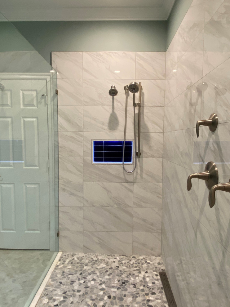Photo of a large beach style master bathroom in Other with shaker cabinets, white cabinets, a curbless shower, a two-piece toilet, gray tile, porcelain tile, pebble tile floors, an undermount sink, engineered quartz benchtops, multi-coloured floor, a hinged shower door, white benchtops, a shower seat, a double vanity and a built-in vanity.