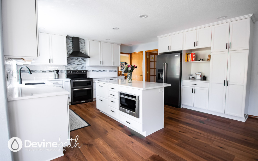 Example of a large transitional l-shaped medium tone wood floor open concept kitchen design in Portland with an undermount sink, recessed-panel cabinets, white cabinets, quartz countertops, white backsplash, glass tile backsplash, stainless steel appliances, an island and white countertops
