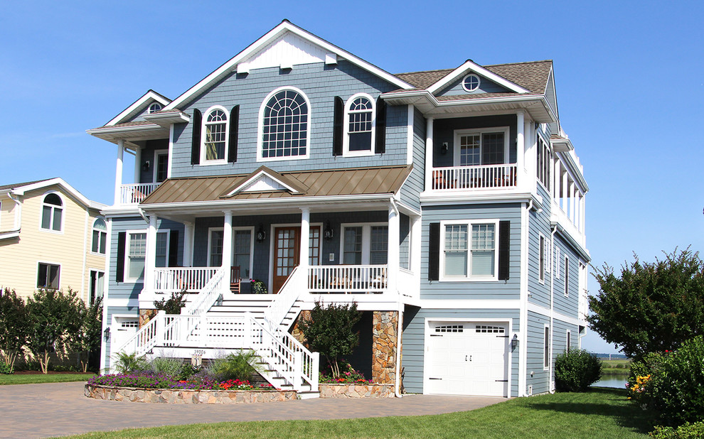 This is an example of an expansive beach style three-storey blue exterior in Other with wood siding.