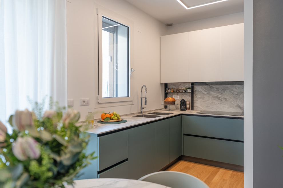 Inspiration for a mid-sized contemporary u-shaped open plan kitchen in Milan with an undermount sink, flat-panel cabinets, green cabinets, solid surface benchtops, grey splashback, engineered quartz splashback, stainless steel appliances, light hardwood floors, no island, beige floor, grey benchtop and recessed.