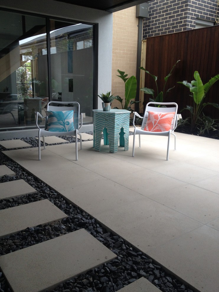 Design ideas for a modern courtyard patio with concrete pavers and a roof extension.