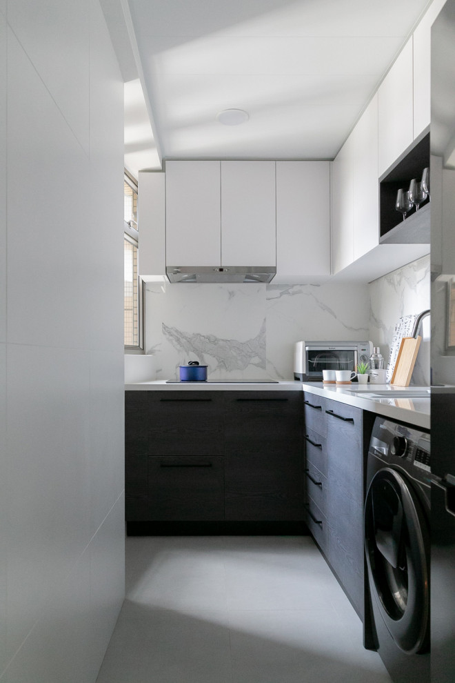Photo of a small modern l-shaped separate kitchen in Hong Kong with a drop-in sink, flat-panel cabinets, black cabinets, limestone benchtops, white splashback, marble splashback, black appliances, ceramic floors, no island, grey floor and white benchtop.