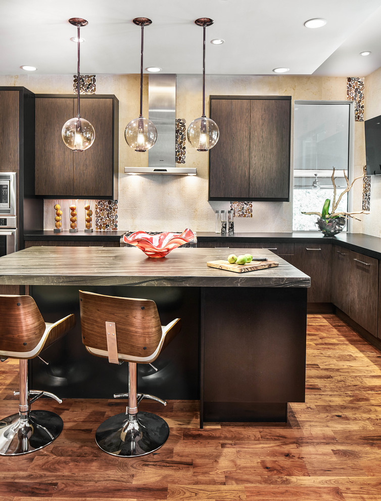 This is an example of a contemporary l-shaped kitchen in Austin with flat-panel cabinets, dark wood cabinets, beige splashback, medium hardwood floors, with island and stone slab splashback.