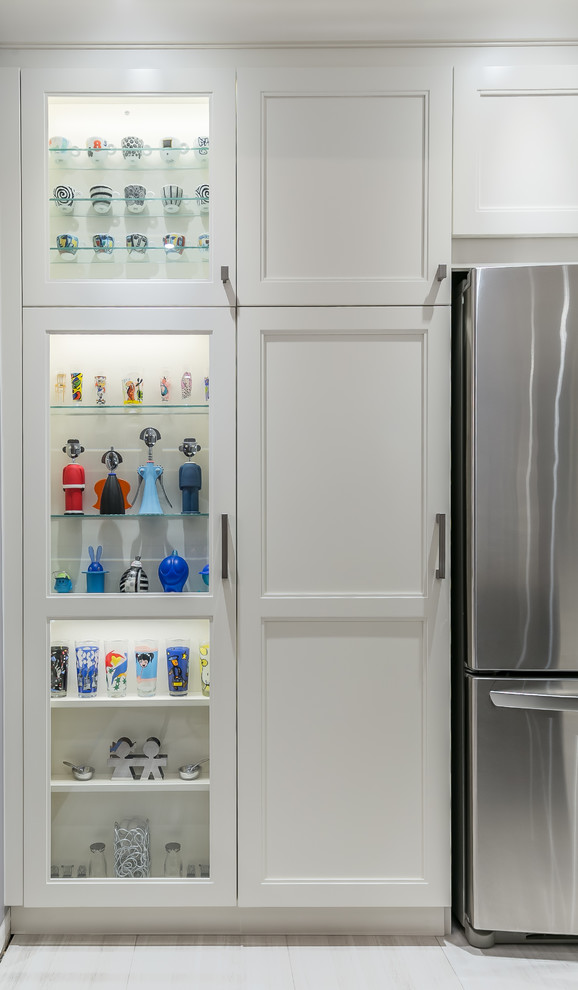 Example of a mid-sized transitional l-shaped porcelain tile eat-in kitchen design in Toronto with a drop-in sink, recessed-panel cabinets, white cabinets, quartz countertops, stainless steel appliances and an island
