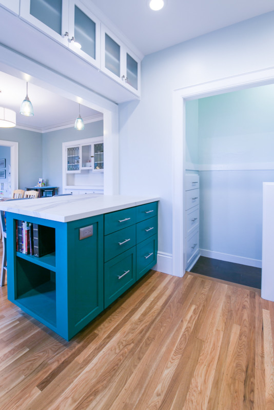 This is an example of an arts and crafts kitchen in San Francisco with a single-bowl sink, raised-panel cabinets, blue cabinets, blue splashback, subway tile splashback, stainless steel appliances, with island and white benchtop.