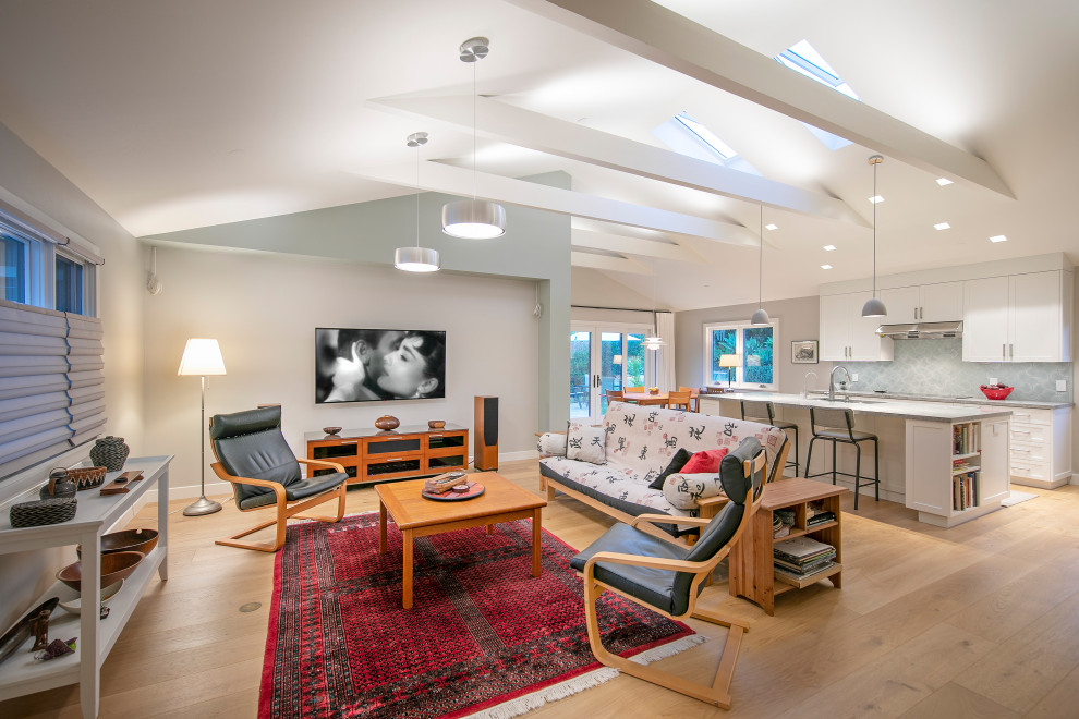 This is an example of a medium sized contemporary open plan living room in Santa Barbara with grey walls, a wall mounted tv and exposed beams.