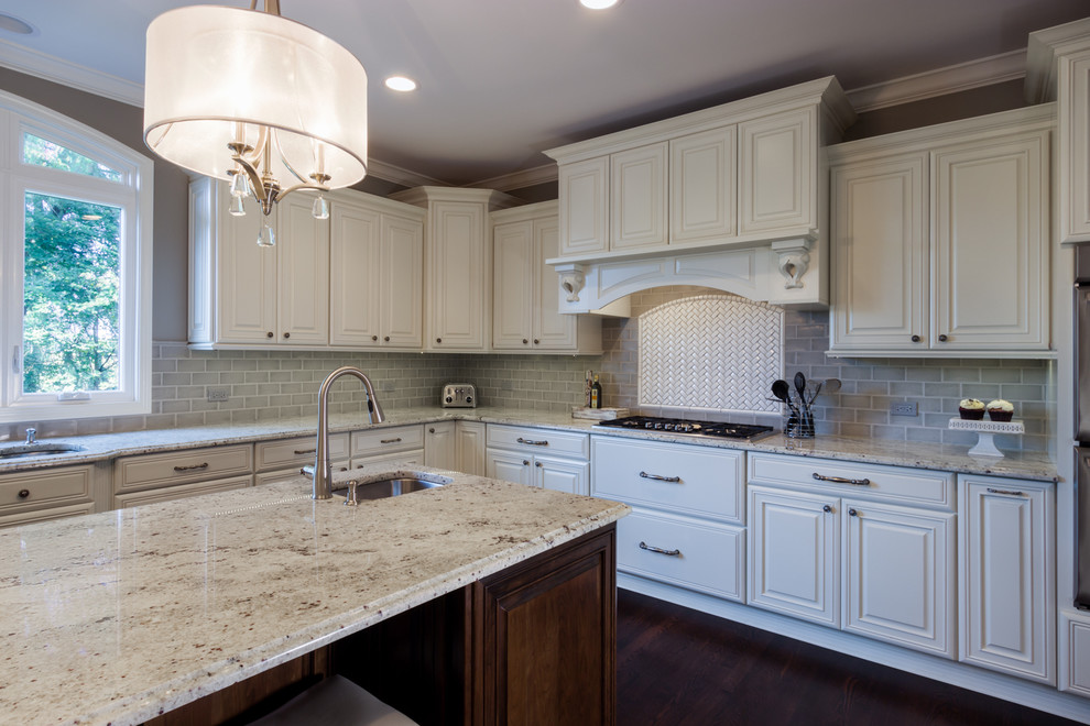 Example of a large transitional u-shaped dark wood floor kitchen design in Chicago with a double-bowl sink, raised-panel cabinets, white cabinets, granite countertops, gray backsplash, subway tile backsplash, stainless steel appliances and an island