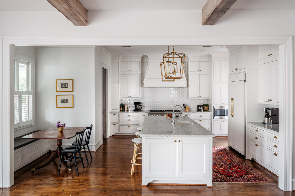 This is an example of a traditional kitchen in Houston with an undermount sink, beaded inset cabinets, white cabinets, marble benchtops, white splashback, subway tile splashback, panelled appliances, medium hardwood floors and with island.