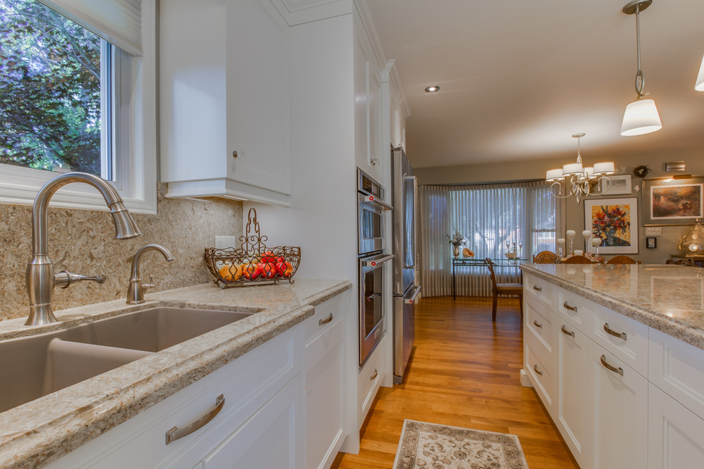 Eat-in kitchen - mid-sized transitional l-shaped medium tone wood floor eat-in kitchen idea in Toronto with an undermount sink, shaker cabinets, white cabinets, quartzite countertops, brown backsplash, stone slab backsplash, stainless steel appliances and an island