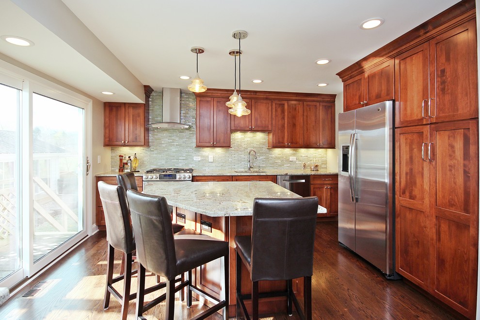 Inspiration for a mid-sized transitional l-shaped eat-in kitchen in Chicago with a single-bowl sink, shaker cabinets, medium wood cabinets, granite benchtops, green splashback, glass tile splashback, stainless steel appliances, dark hardwood floors and with island.