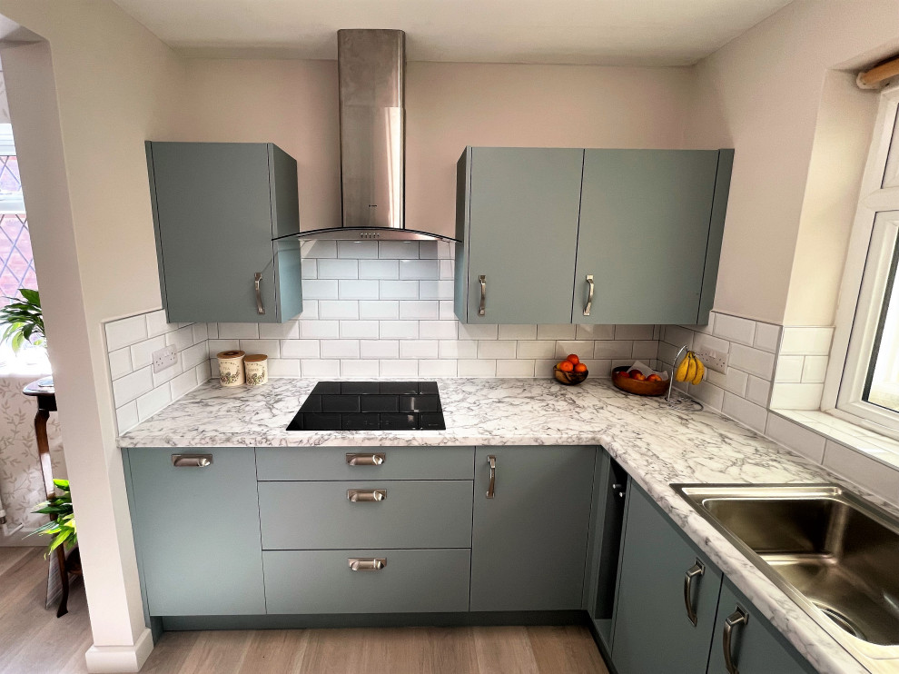 Medium sized modern galley enclosed kitchen in Other with a built-in sink, flat-panel cabinets, green cabinets, laminate countertops, white splashback, porcelain splashback, black appliances, light hardwood flooring, no island, brown floors and white worktops.