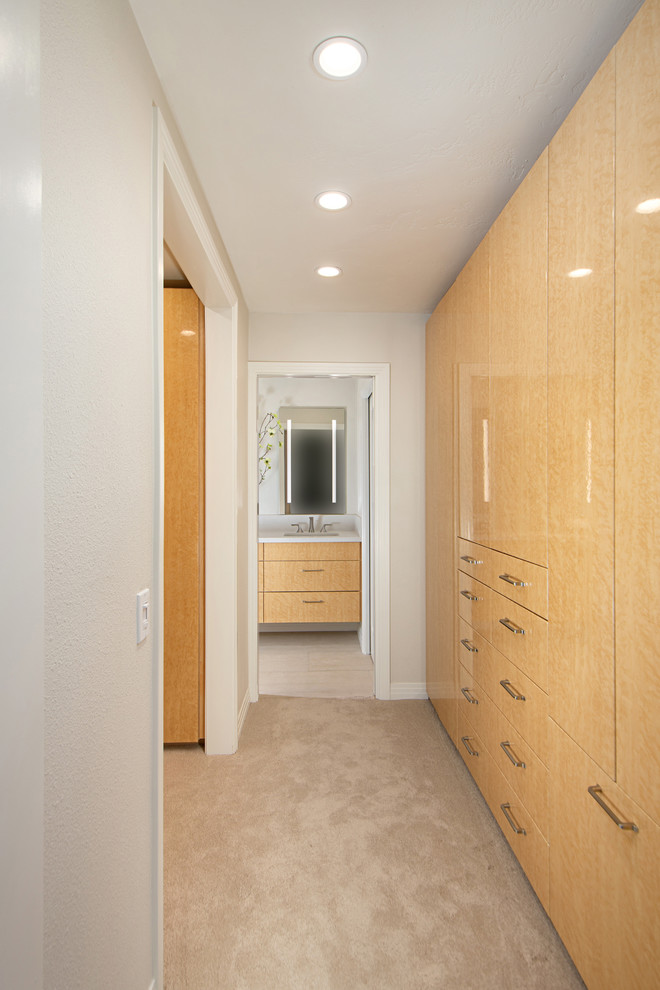 Inspiration for a mid-sized transitional women's dressing room in San Diego with flat-panel cabinets, light wood cabinets, carpet and beige floor.