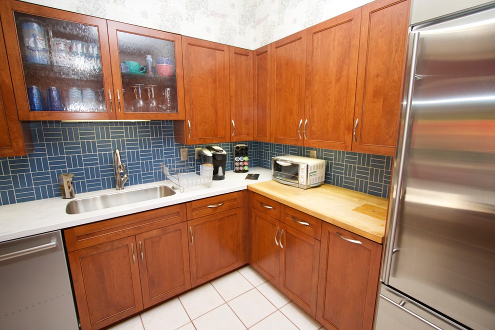 Transitional l-shaped ceramic tile open concept kitchen photo in Baltimore with an undermount sink, recessed-panel cabinets, medium tone wood cabinets, solid surface countertops, blue backsplash, ceramic backsplash, stainless steel appliances and an island