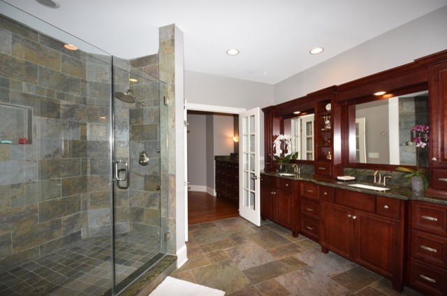 Inspiration for a large traditional master bathroom in Chicago with raised-panel cabinets, dark wood cabinets, a corner tub, an alcove shower, a two-piece toilet, gray tile, slate, grey walls, slate floors, an undermount sink, granite benchtops, grey floor and a hinged shower door.