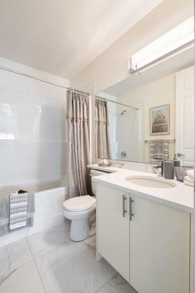 Design ideas for a beach style bathroom in Calgary with flat-panel cabinets, white cabinets, an alcove tub, a shower/bathtub combo, a two-piece toilet, white tile, subway tile, white walls, an undermount sink, solid surface benchtops, grey floor, a shower curtain and white benchtops.