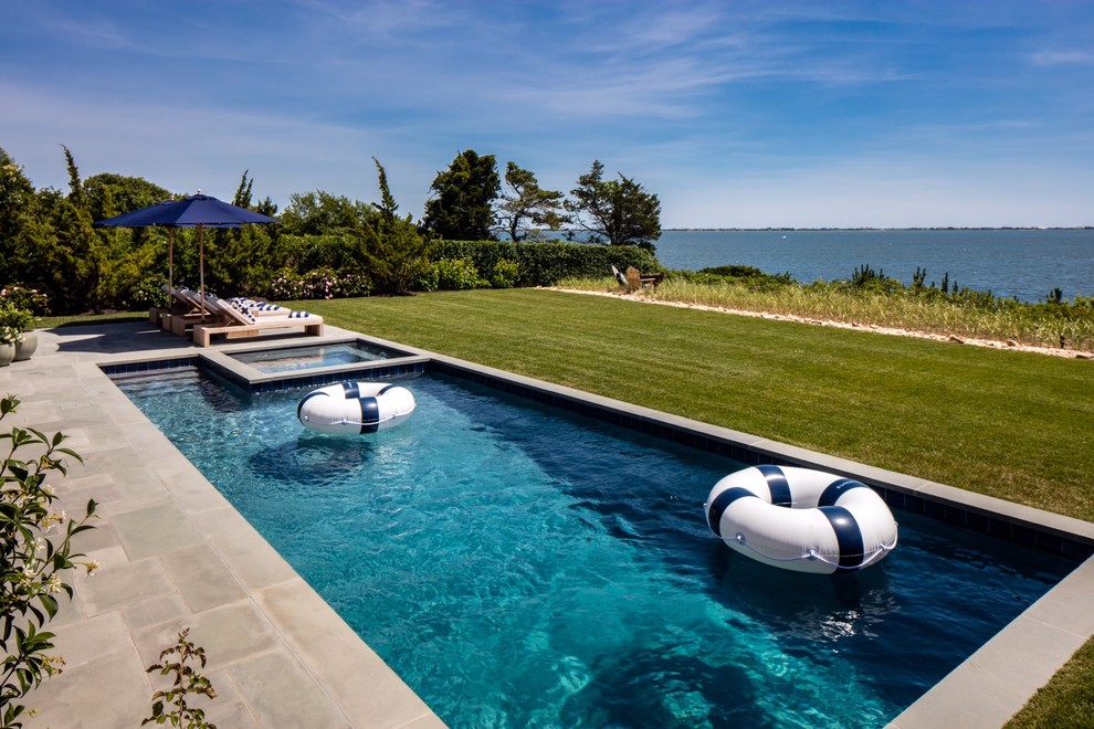 Large beach style backyard rectangular pool in New York with a hot tub and concrete slab.