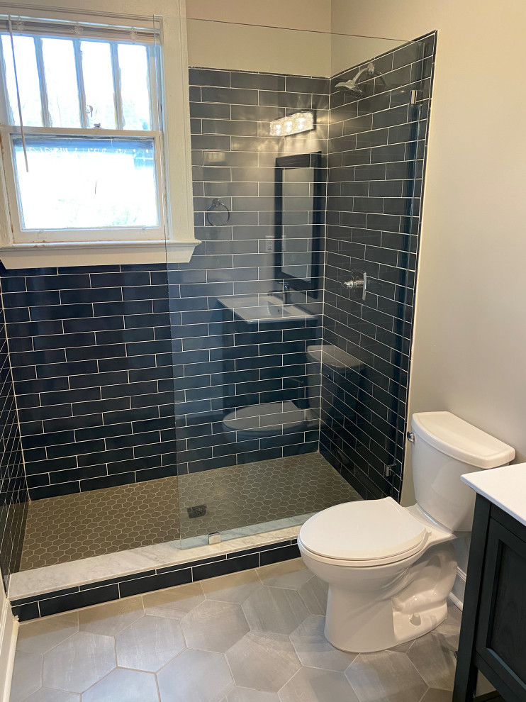 Photo of a mid-sized scandinavian master bathroom in Other with furniture-like cabinets, black cabinets, an open shower, a one-piece toilet, blue tile, glass sheet wall, white walls, ceramic floors, a console sink, granite benchtops, grey floor, a hinged shower door, white benchtops, a single vanity, a floating vanity, wood and wood walls.