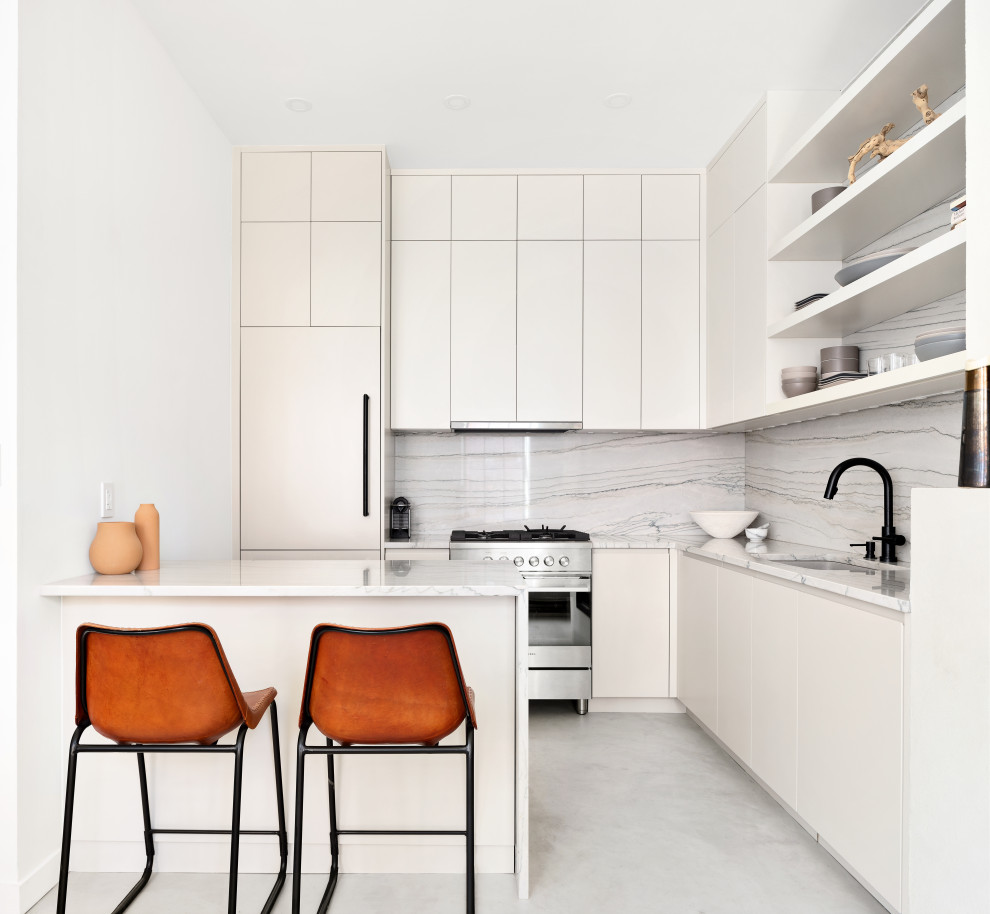 Photo of a small contemporary l-shaped kitchen in New York with an undermount sink, flat-panel cabinets, beige cabinets, quartzite benchtops, beige splashback, stone slab splashback, panelled appliances, concrete floors, beige benchtop, a peninsula and grey floor.