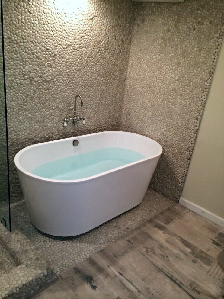 Idee per un'ampia stanza da bagno padronale stile marino con vasca/doccia, piastrelle beige, piastrelle di ciottoli, pareti beige, pavimento in gres porcellanato e vasca freestanding