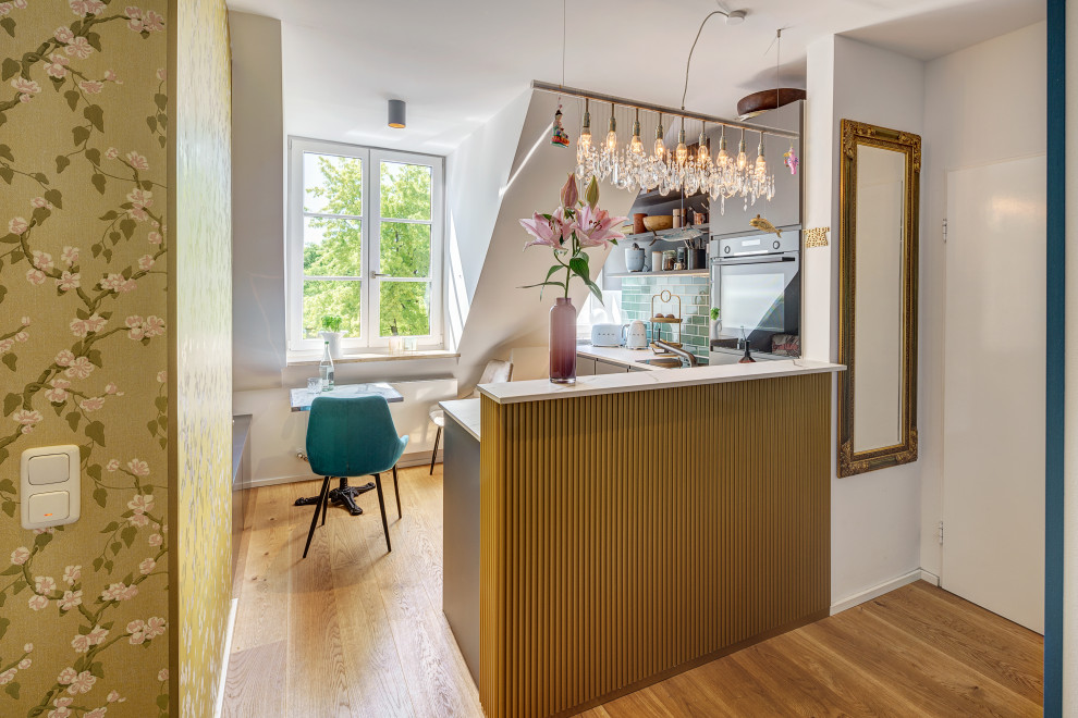 Inspiration for a small eclectic l-shaped open plan kitchen in Munich with black cabinets, engineered stone countertops, green splashback, metro tiled splashback, medium hardwood flooring and white worktops.