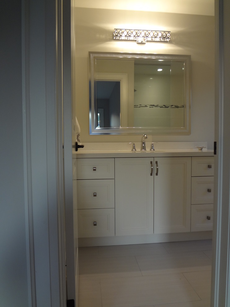 This is an example of an expansive contemporary bathroom in Toronto with an undermount sink, shaker cabinets, white cabinets, quartzite benchtops, a corner tub, a curbless shower, a one-piece toilet, white tile, porcelain tile, white walls and porcelain floors.