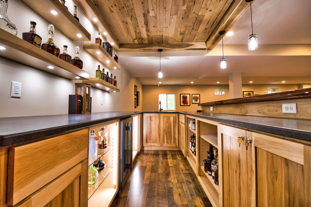 Inspiration for a large rustic u-shaped laminate floor and brown floor wet bar remodel in Cincinnati with an undermount sink, shaker cabinets, light wood cabinets, granite countertops and black countertops