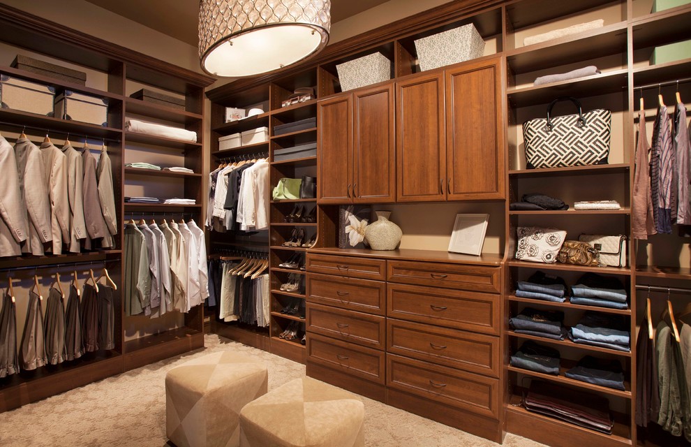 Large traditional gender-neutral walk-in wardrobe in Charleston with recessed-panel cabinets, medium wood cabinets, carpet and brown floor.