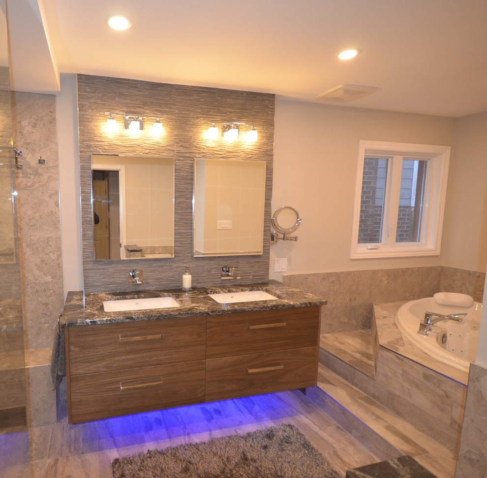 This is an example of a contemporary master bathroom in Ottawa with flat-panel cabinets, medium wood cabinets, a hot tub, a curbless shower, gray tile, porcelain tile, porcelain floors, an undermount sink and granite benchtops.