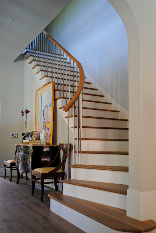 This is an example of a large transitional wood curved staircase in Dallas with painted wood risers.