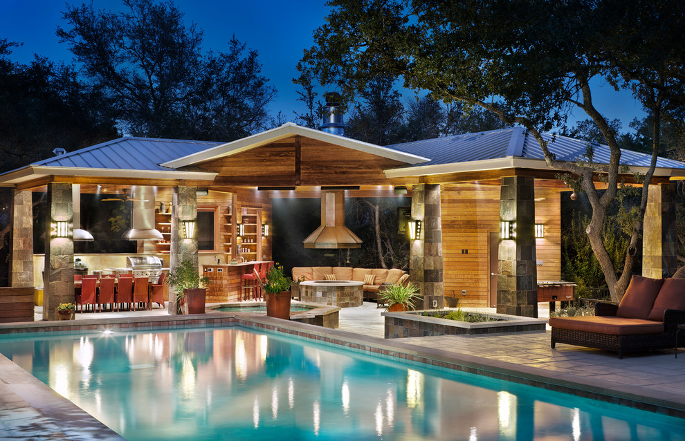 Photo of an expansive transitional backyard custom-shaped pool in Austin with a pool house and concrete pavers.