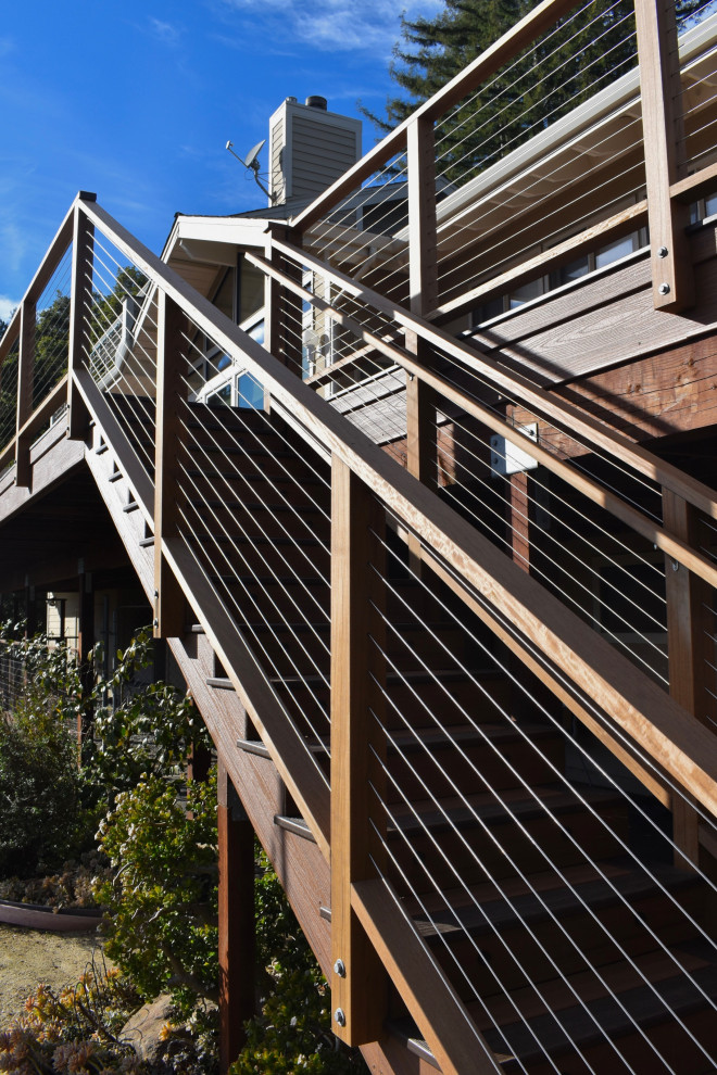 Example of a minimalist backyard ground level cable railing deck design