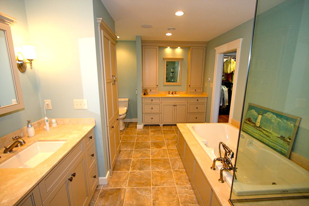 Large traditional master bathroom in Boston with beaded inset cabinets, beige cabinets, a drop-in tub, a corner shower, a two-piece toilet, blue walls, ceramic floors, an undermount sink, limestone benchtops and a hinged shower door.