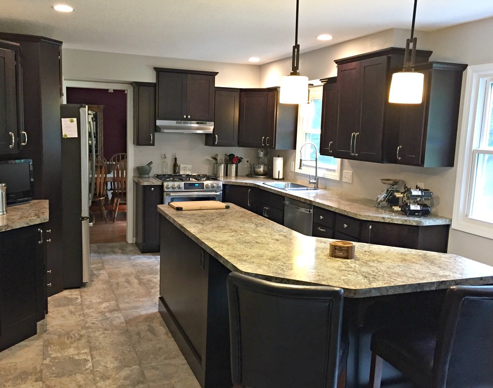 Inspiration for a mid-sized transitional l-shaped limestone floor open concept kitchen remodel with a drop-in sink, shaker cabinets, dark wood cabinets, granite countertops, stainless steel appliances and an island