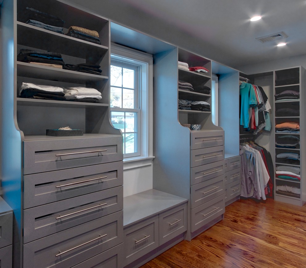 Photo of a large traditional gender-neutral walk-in wardrobe in New York with shaker cabinets, grey cabinets, medium hardwood floors and brown floor.