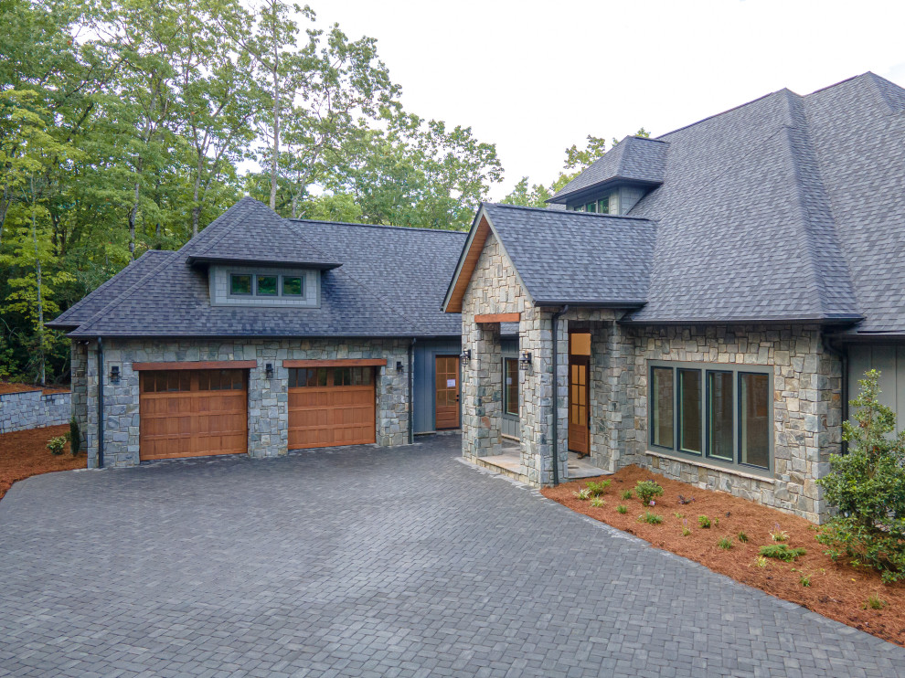 Large modern one-storey grey house exterior with mixed siding, a butterfly roof, a shingle roof and a grey roof.