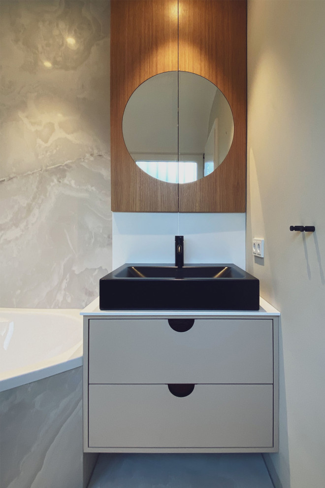 This is an example of a medium sized contemporary grey and white bathroom in Dusseldorf with flat-panel cabinets, a corner bath, a wall mounted toilet, grey tiles, ceramic tiles, beige walls, ceramic flooring, a vessel sink, grey floors, black worktops, a single sink and a built in vanity unit.