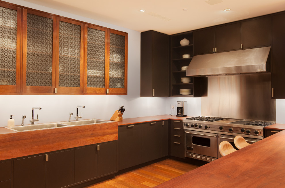 Design ideas for a contemporary u-shaped kitchen in New York with a drop-in sink, flat-panel cabinets, dark wood cabinets, wood benchtops and stainless steel appliances.