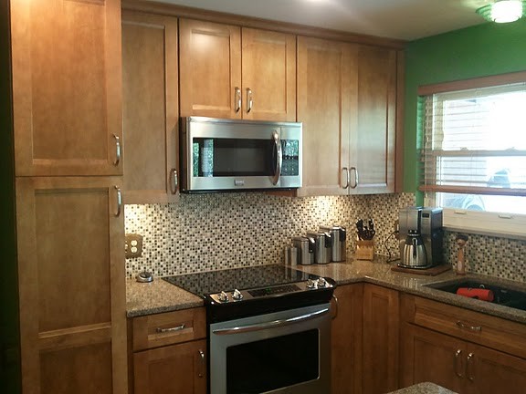 Inspiration for a mid-sized transitional u-shaped medium tone wood floor eat-in kitchen remodel in Cincinnati with an undermount sink, flat-panel cabinets, medium tone wood cabinets, quartz countertops, multicolored backsplash, mosaic tile backsplash, stainless steel appliances and an island
