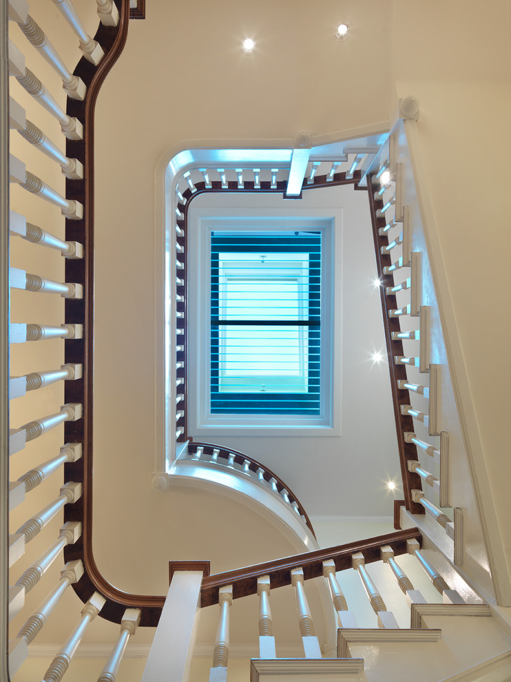 This is an example of a large transitional wood curved staircase in Boston with wood risers.