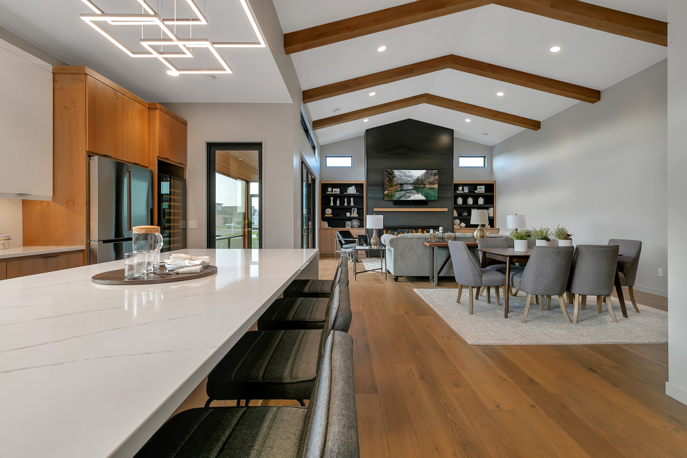 Mid-sized modern l-shaped kitchen in Minneapolis with flat-panel cabinets, light wood cabinets, granite benchtops, white splashback, granite splashback, stainless steel appliances, light hardwood floors, with island and white benchtop.