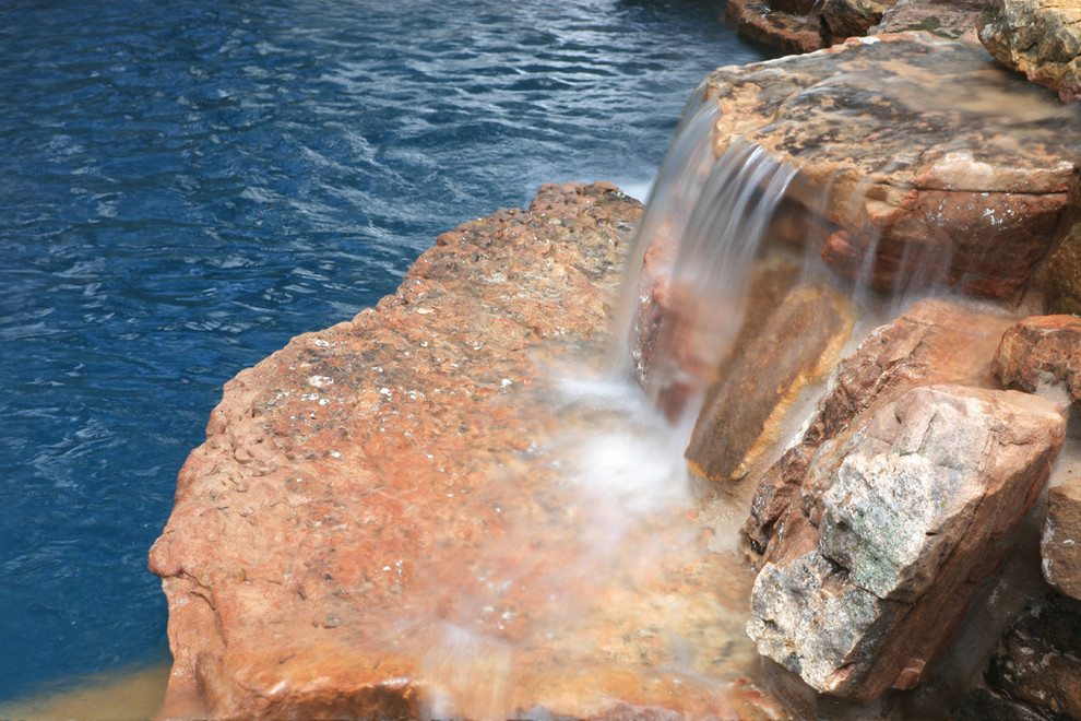 Example of a mid-sized mountain style backyard stone and custom-shaped natural pool fountain design in Austin