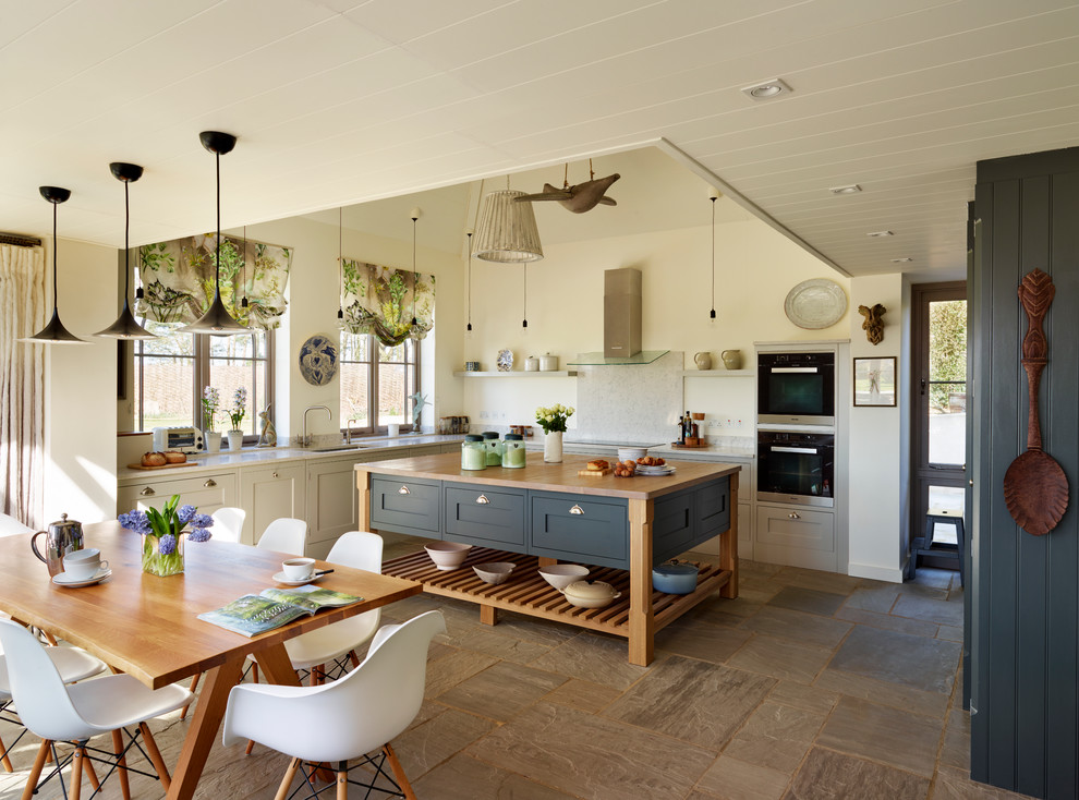 Large beach style l-shaped open plan kitchen in Essex with grey cabinets, wood benchtops and with island.